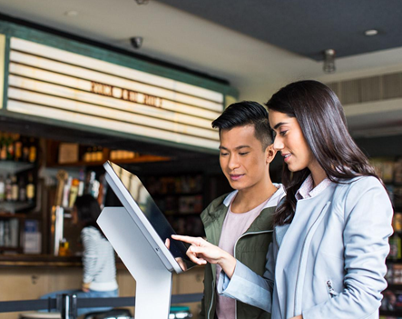 Image of two smiling people looking at a digital signage kiosk